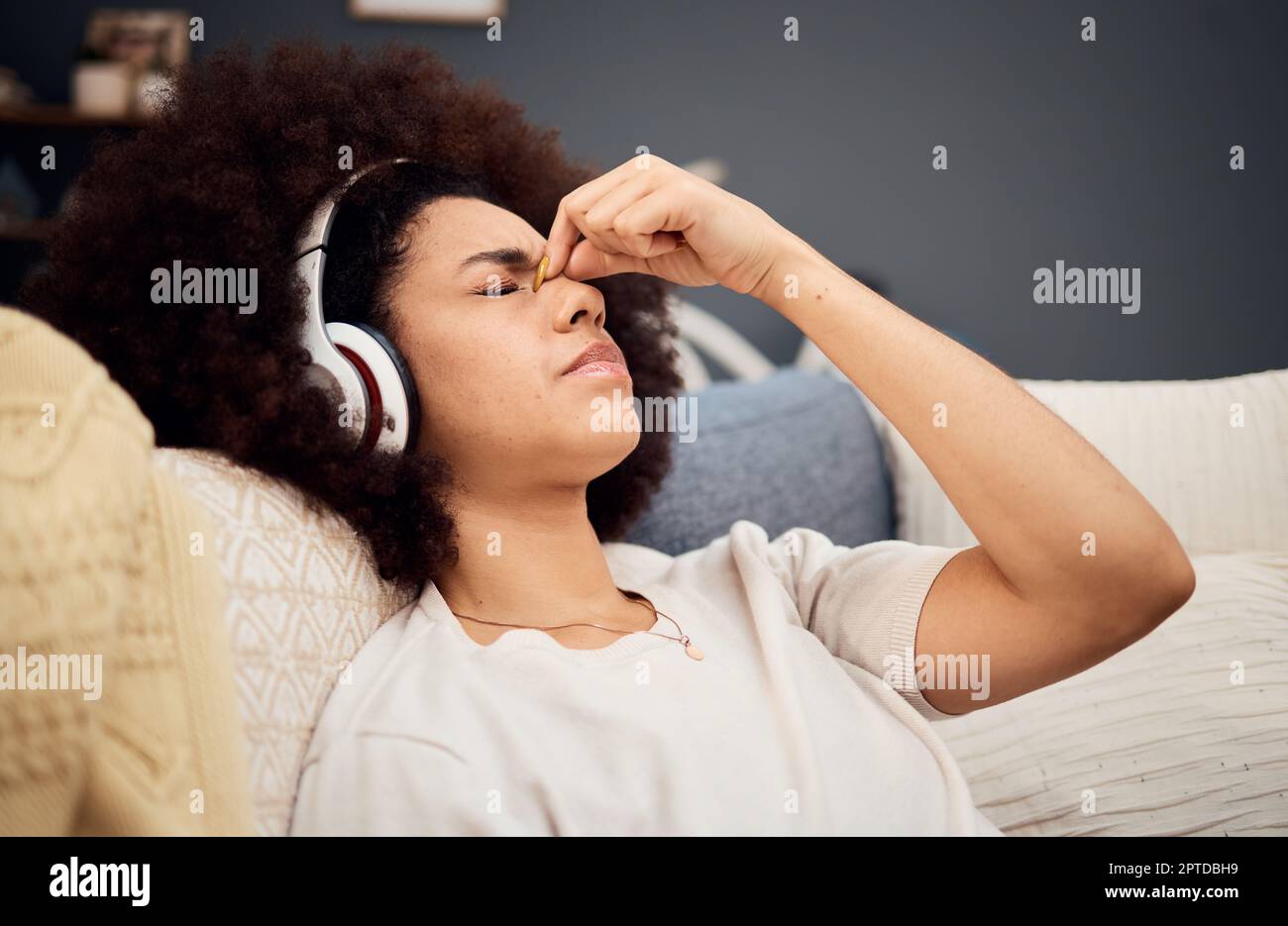 Dolor de cabeza, dolor y mujer con auriculares de sofá cansados, agotados y  tratando de relajarse. El estrés, la fatiga y la mujer negra escuchando  música en casa stre Fotografía de stock -