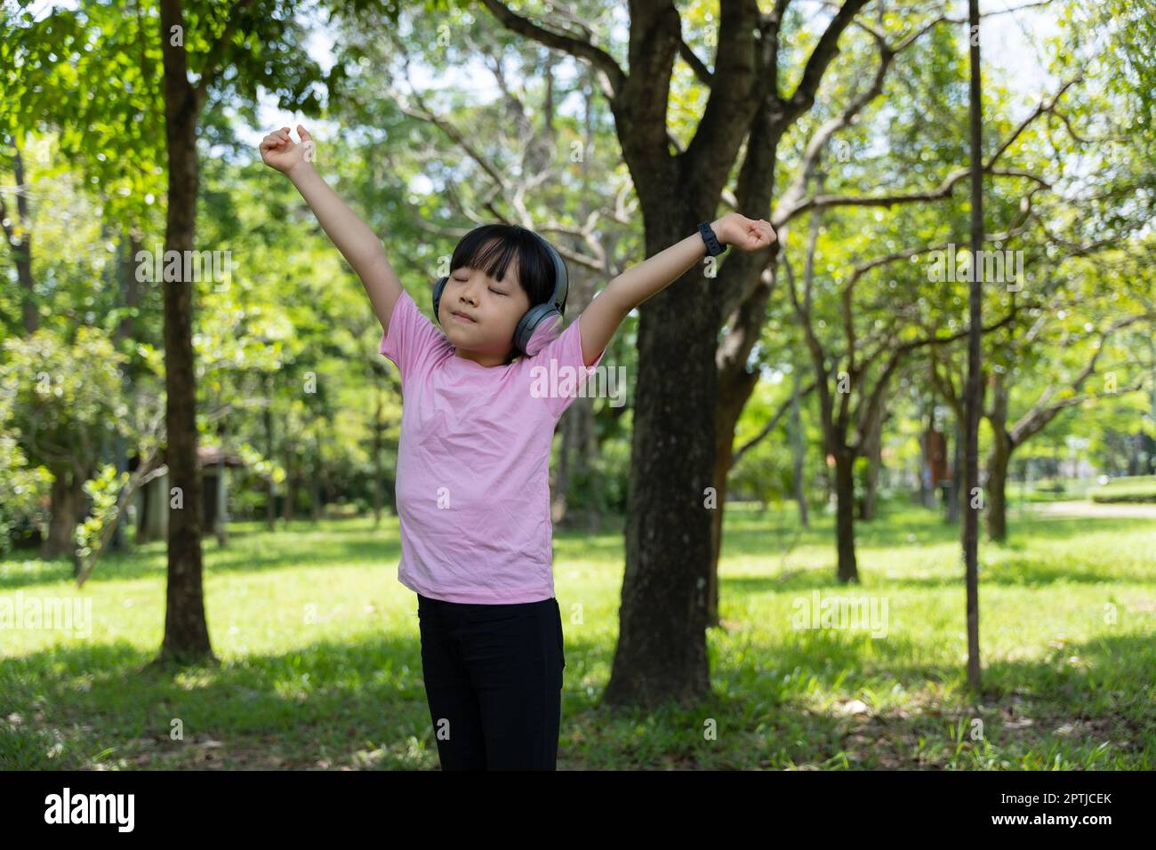 Una niña pequeña con auriculares inalámbricos negros grandes sobre un fondo  rosa pastel mira la cámara. El concepto de escuchar y disfrutar de la  música. Colocar para texto, espacio de copia Fotografía de stock - Alamy