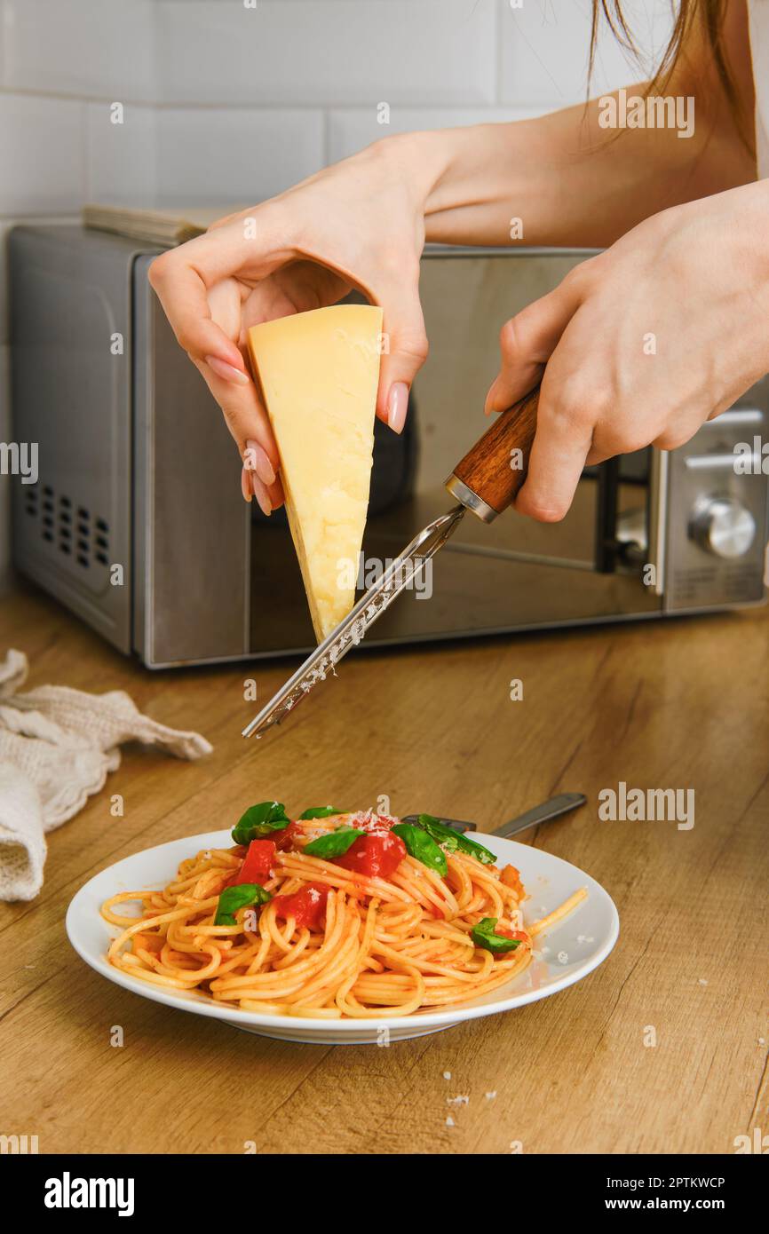 https://c8.alamy.com/compes/2ptkwcp/vista-de-primer-plano-del-parmesano-rallado-a-mano-sobre-un-plato-de-pasta-en-la-cocina-2ptkwcp.jpg