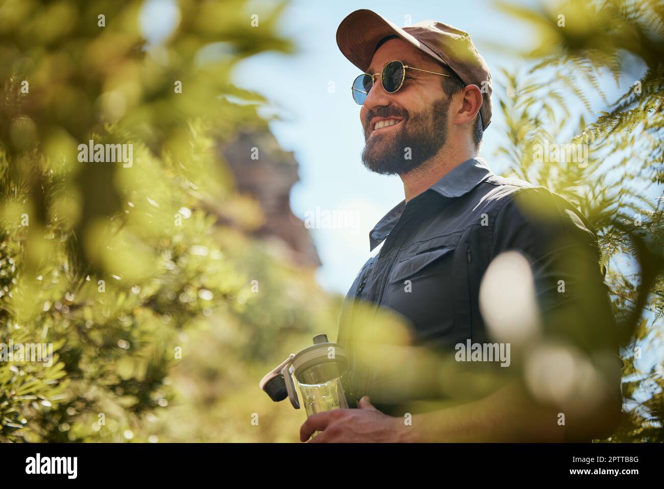Hombre de ajuste aventurero con gafas y una gorra mientras camina o explora  el bosque. Hombre guapo con barba sonriendo mientras explora la naturaleza  en el f Fotografía de stock - Alamy