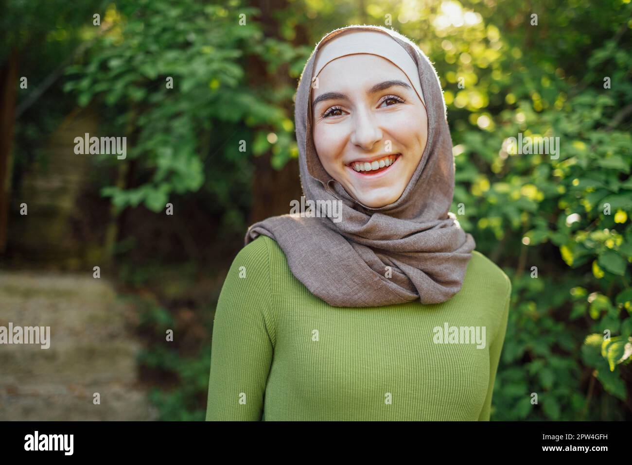 Hermosa adolescente alegre niña de la escuela secundaria usando ropa musulmana colorida divertirse al aire libre Foto de stock
