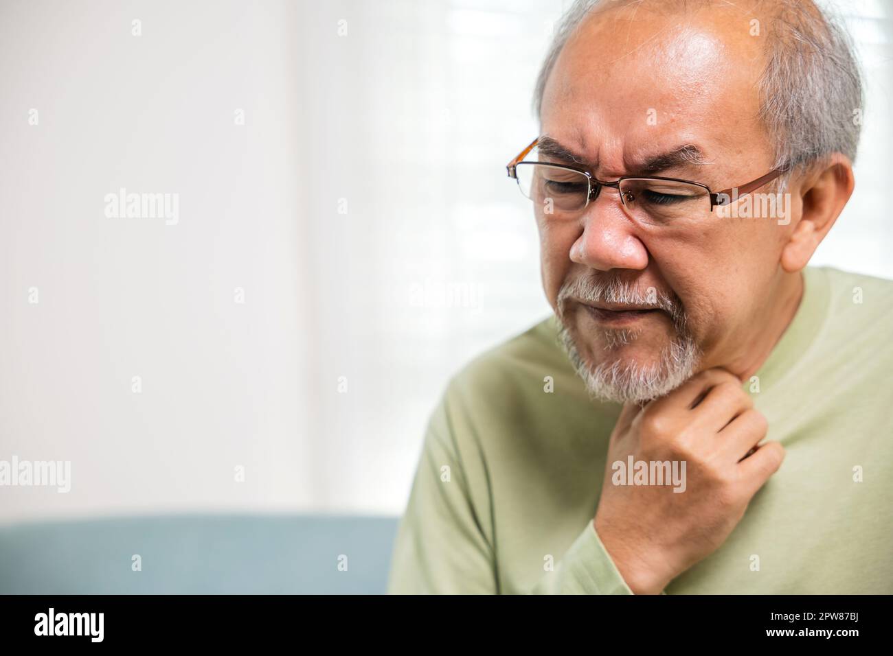 Viejo asiático doloroso en la garganta dolorida, anciano del retiro sintiendo dolor usar las manos sosteniendo el cuello, las personas mayores tienen disfagia debido a comer, curan Foto de stock