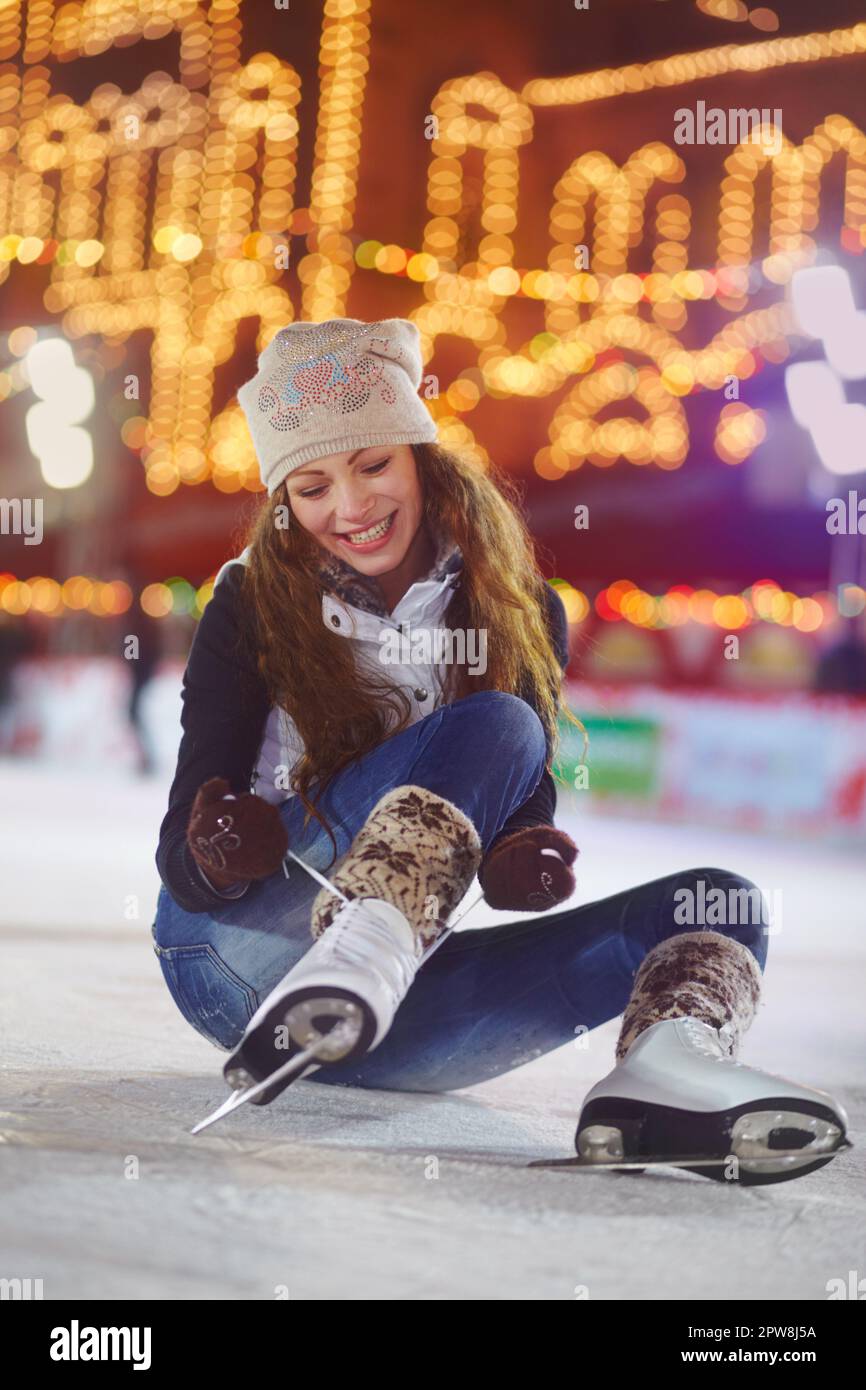 Sonría, patinaje sobre hielo y zapatos de mujer en la pista para comenzar a  hacer ejercicio físico, ejercicio y entrenamiento por la noche. Skater,  felicidad y persona femenina que ata patines para