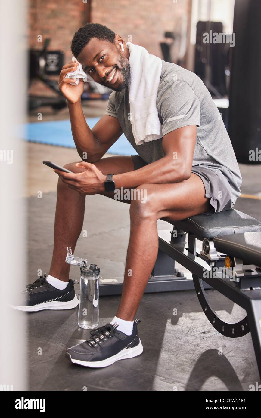 Fitness hombre vistiendo ropa deportiva enviando mensajes de texto por  teléfono en el gimnasio