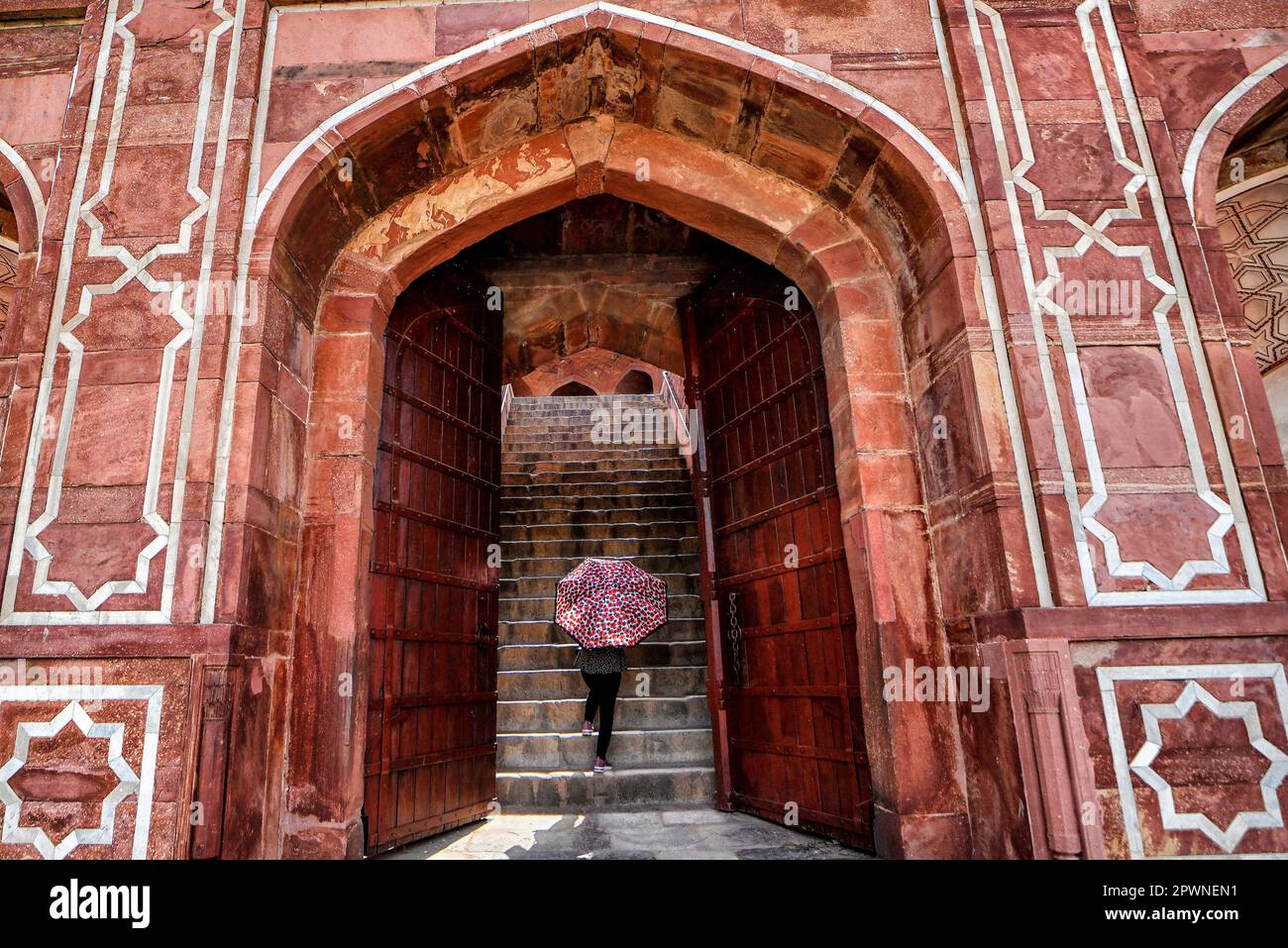Un visitante que sostiene un paraguas camina dentro del patio de la