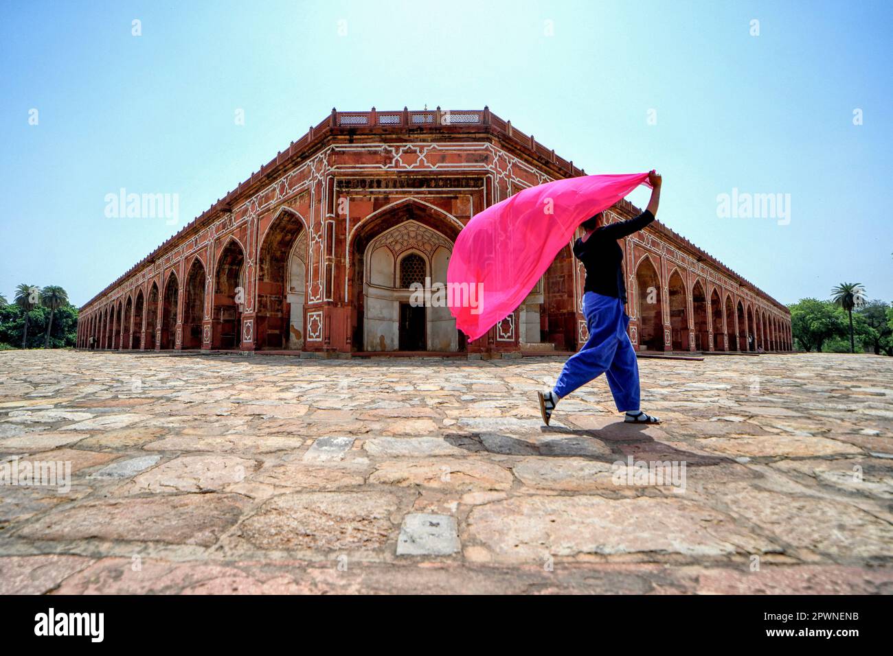 Una mujer con una bufanda colorida camina dentro del patio de la tumba