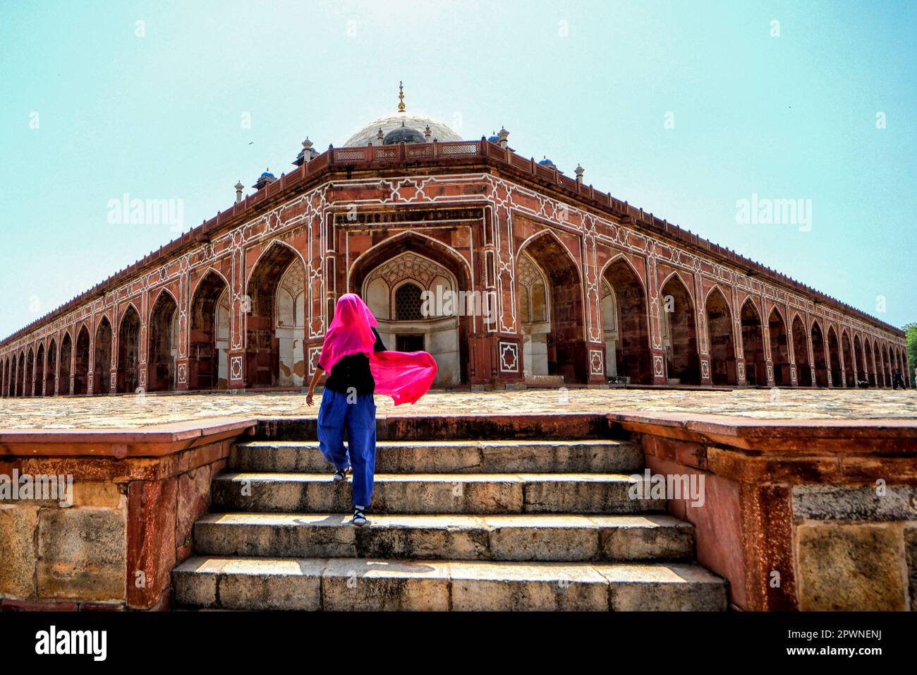 Una mujer con una bufanda colorida camina dentro del patio de la tumba