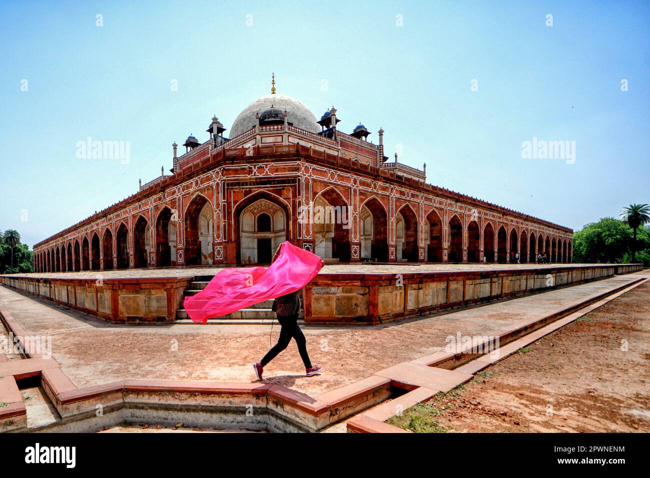Una mujer con una bufanda colorida camina dentro del patio de la tumba