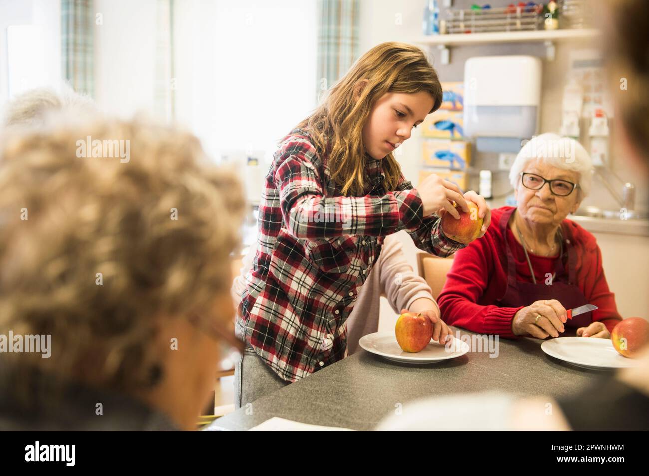 Mujeres mayores con niña pelando manzana en casa de descanso Foto de stock