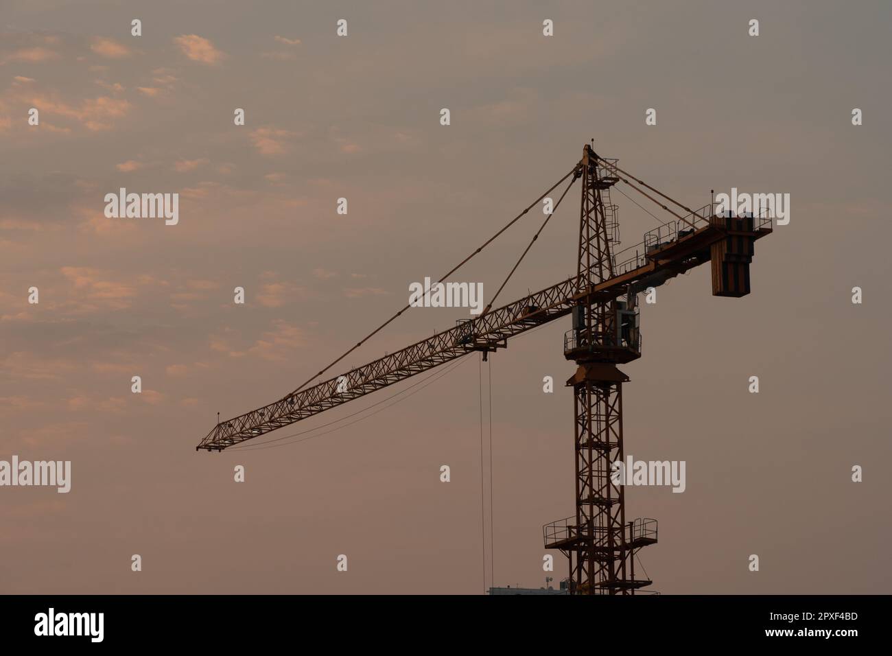 vista de una grúa de torre solitaria al atardecer con un fondo de cielo. Foto de stock