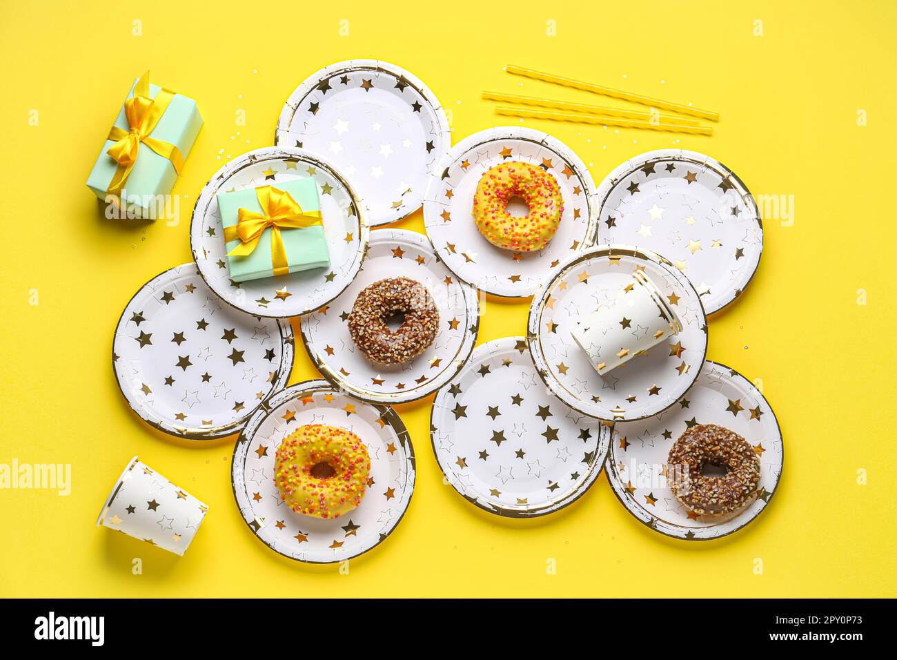Vajilla desechable de papel con donuts y regalos de cumpleaños sobre fondo  amarillo Fotografía de stock - Alamy