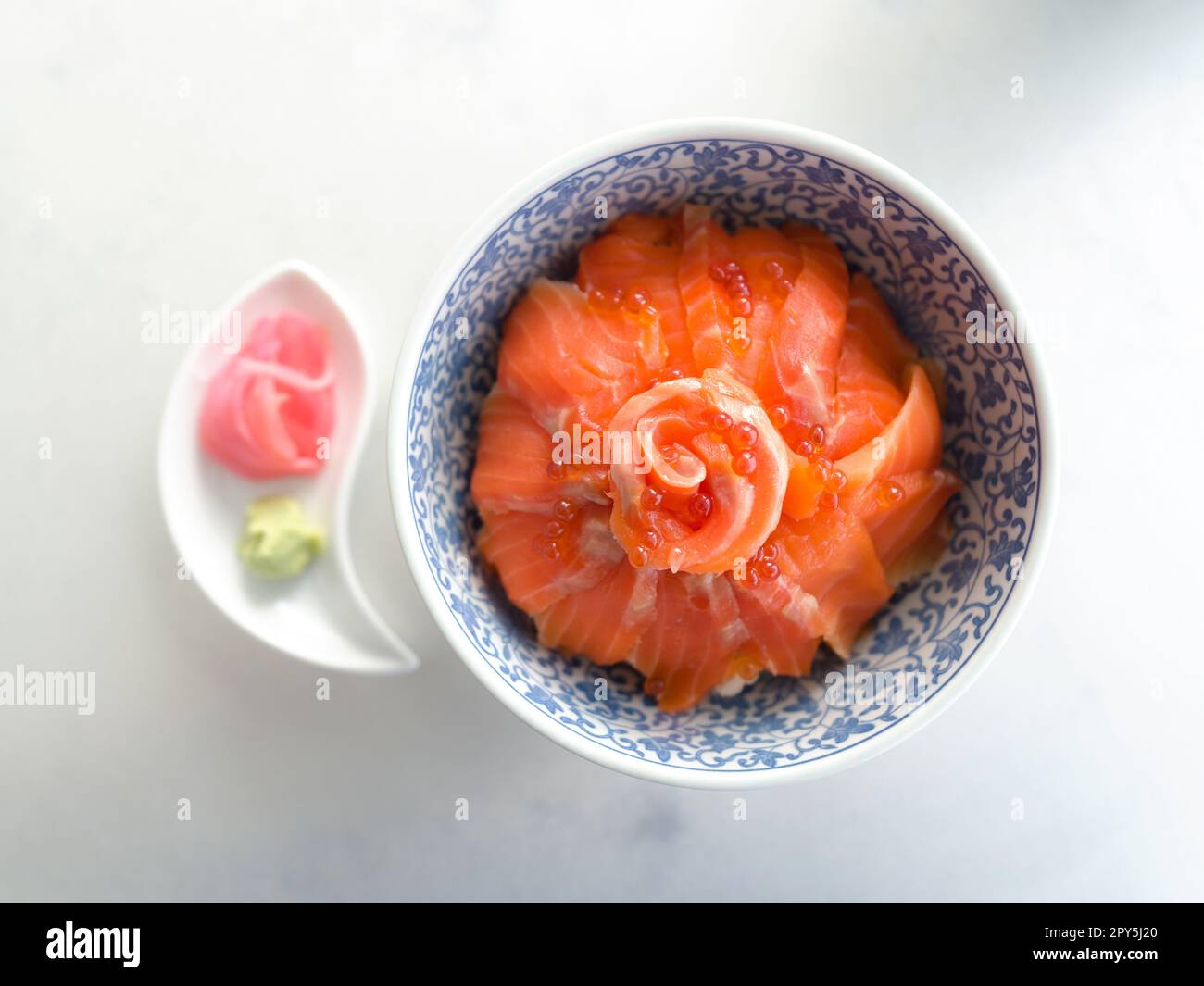 Primer plano â rebanadas de â salmón y hueva de salmón (ikura) en un tazón de arroz sashimi. Foto de stock