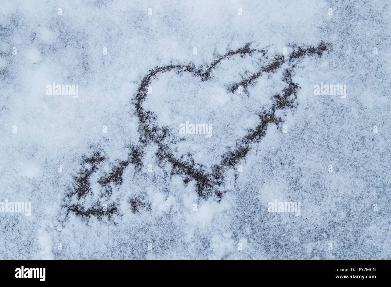 Día de San Valentín. Corazón atravesado por una flecha dibujada sobre la nieve. Foto de stock
