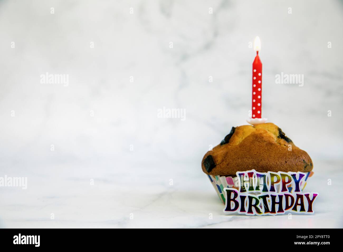 Cupcake de cumpleaños con una vela roja de pastel de cumpleaños sobre un fondo blanco con copyspace a un lado, feliz cumpleaños, concepto de fiesta Foto de stock