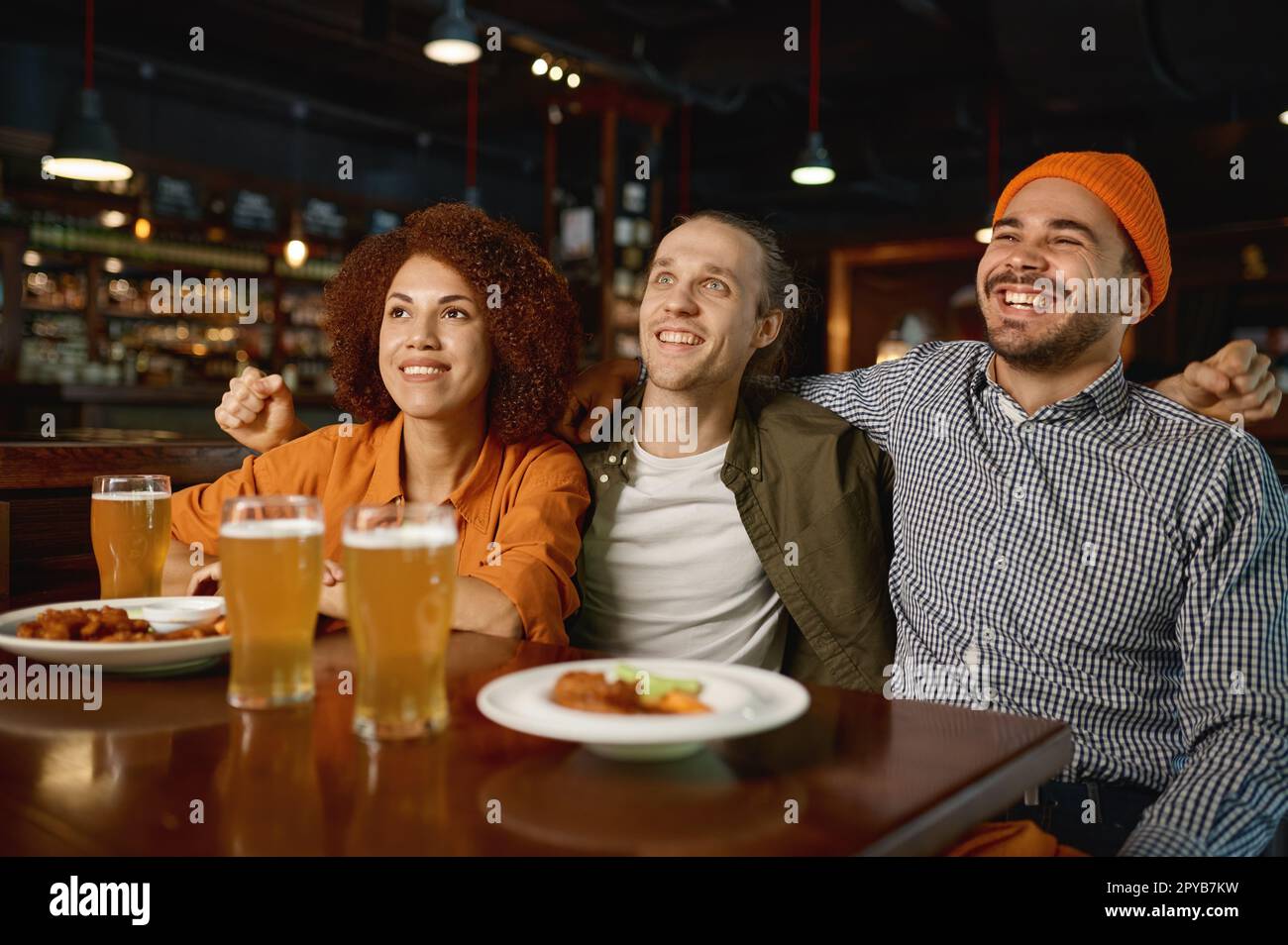 Jóvenes viendo partido de fútbol en el bar deportivo Foto de stock