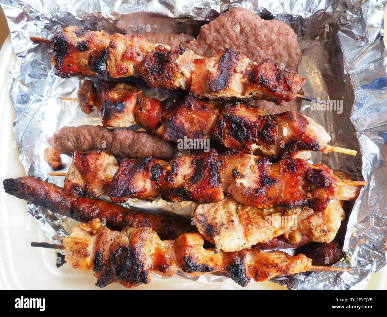 Carne a la parrilla en embalaje desechable y papel de aluminio, entregado desde un restaurante. Entrega de comida a domicilio de restaurantes y cafeterías. Shish kebab y carne grumosa de pollo, cerdo y cordero Foto de stock