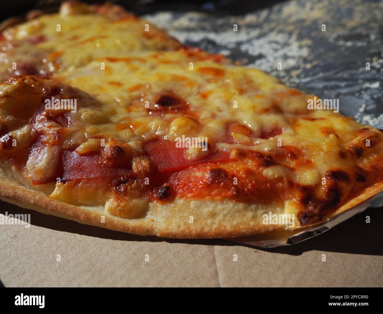 Pizza con tomates y queso en una caja de cartón y papel de aluminio. Deliciosa pizza de cerca. Mensajería de entrega de alimentos a su casa. Pedir pizza. Pastel de levadura redondo italiano tradicional con relleno Foto de stock