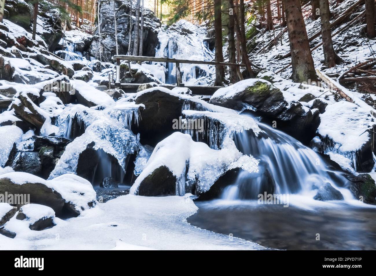 cascadas congeladas con una barandilla de madera en el bosque durante el senderismo Foto de stock