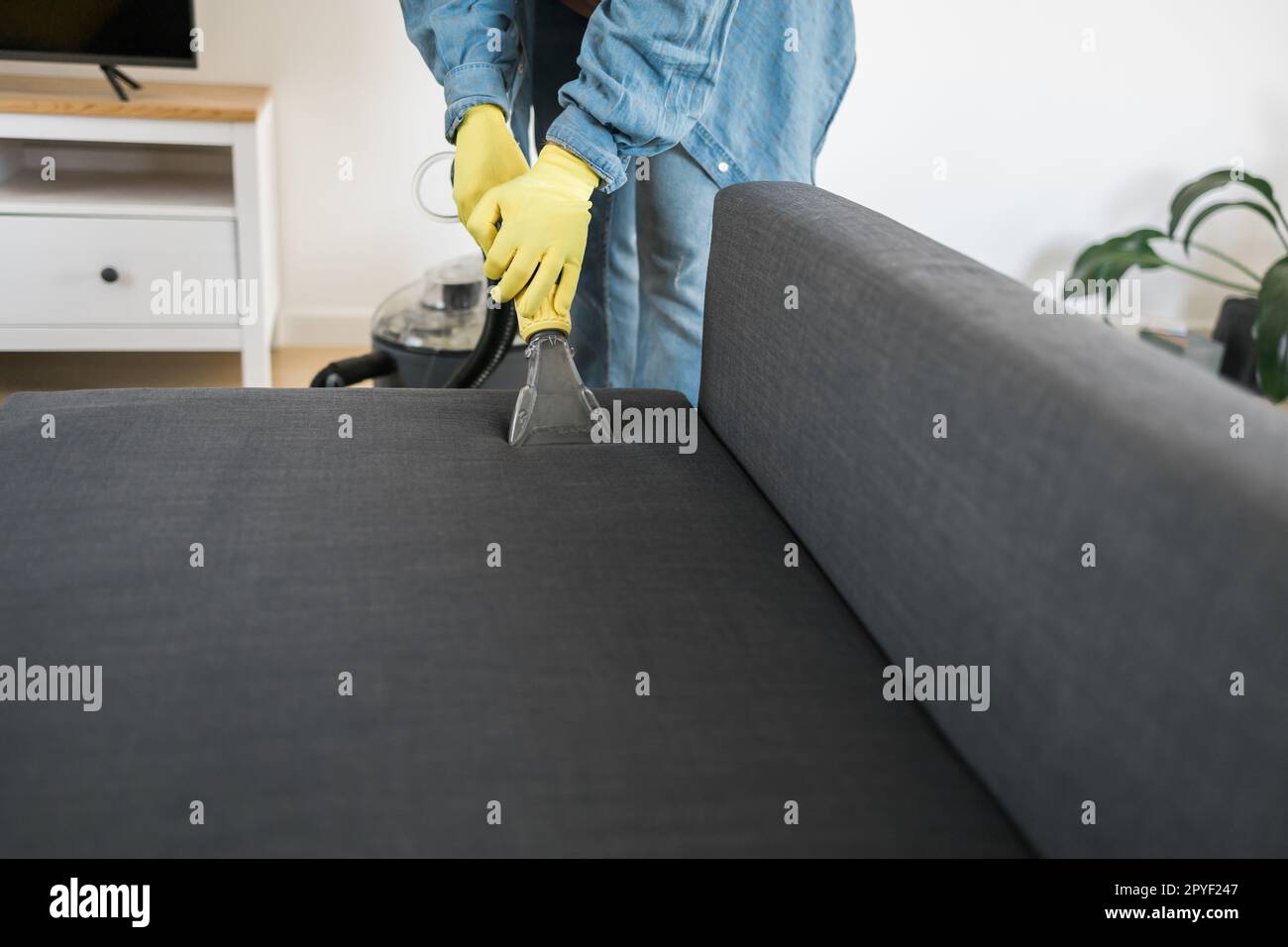 Hombre vertiendo un líquido para limpiar e impermeabilizar los cojines del  sofá