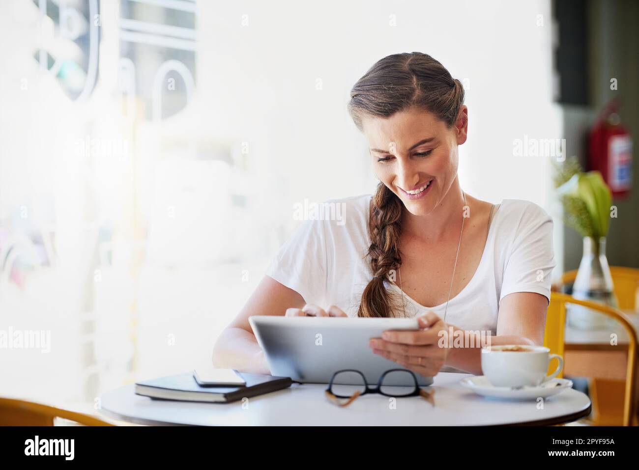 La señal wifi aquí es tan fuerte como el café. una mujer joven relajada usando su tableta mientras bebía café en su café favorito. Foto de stock