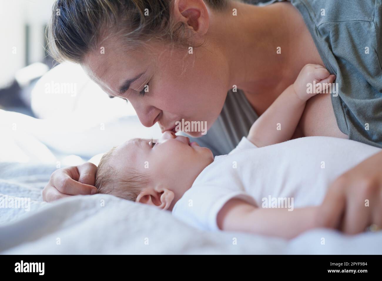 Nada tan tierno como el amor de una madre. una mujer joven que se une con su bebé en casa. Foto de stock