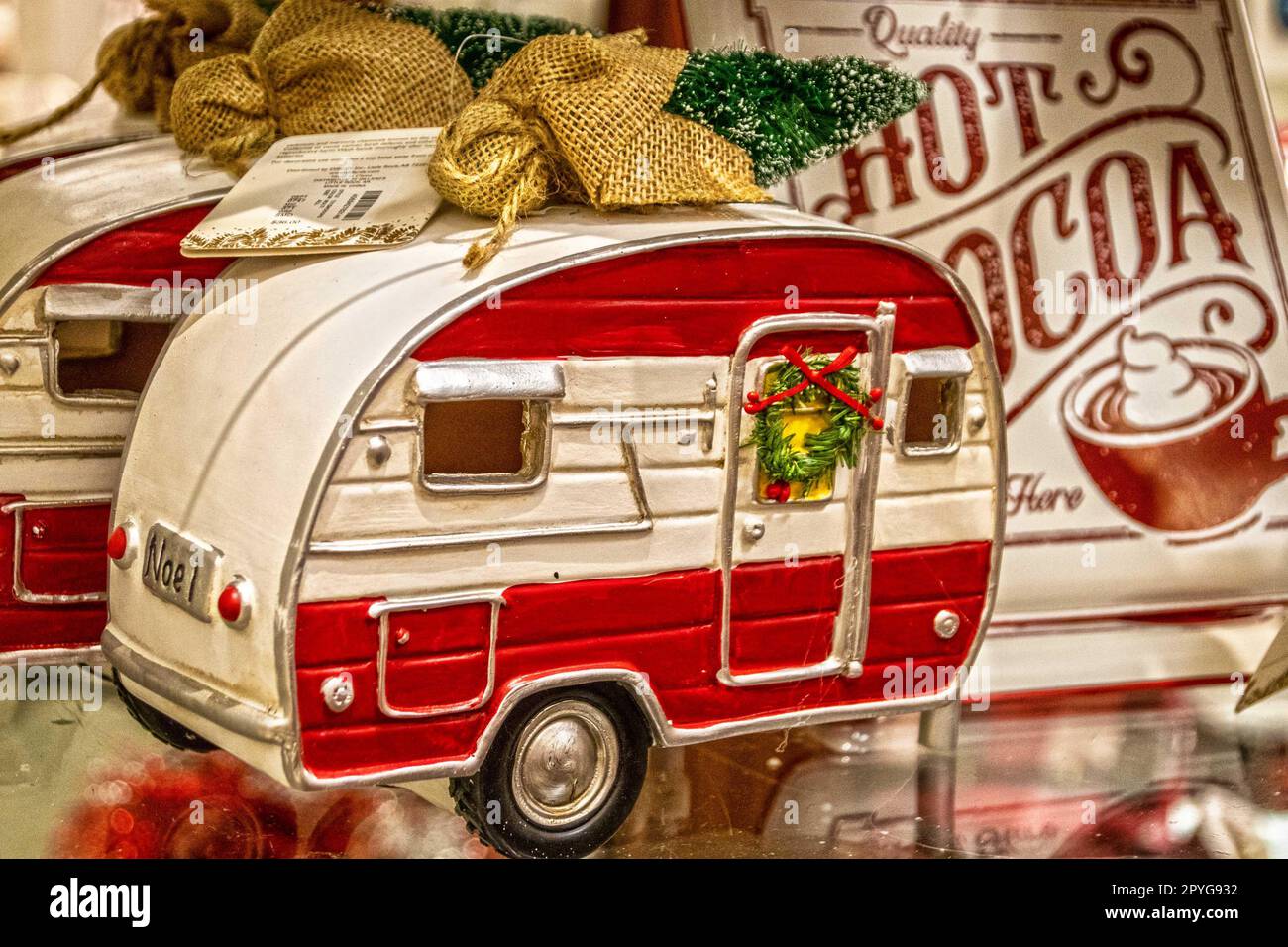 Adorno de Navidad retro Vintage Camper Trailer con corona en la puerta y árbol de Navidad en la parte superior sobre fondo difuminado, incluido el signo de chocolate caliente Foto de stock