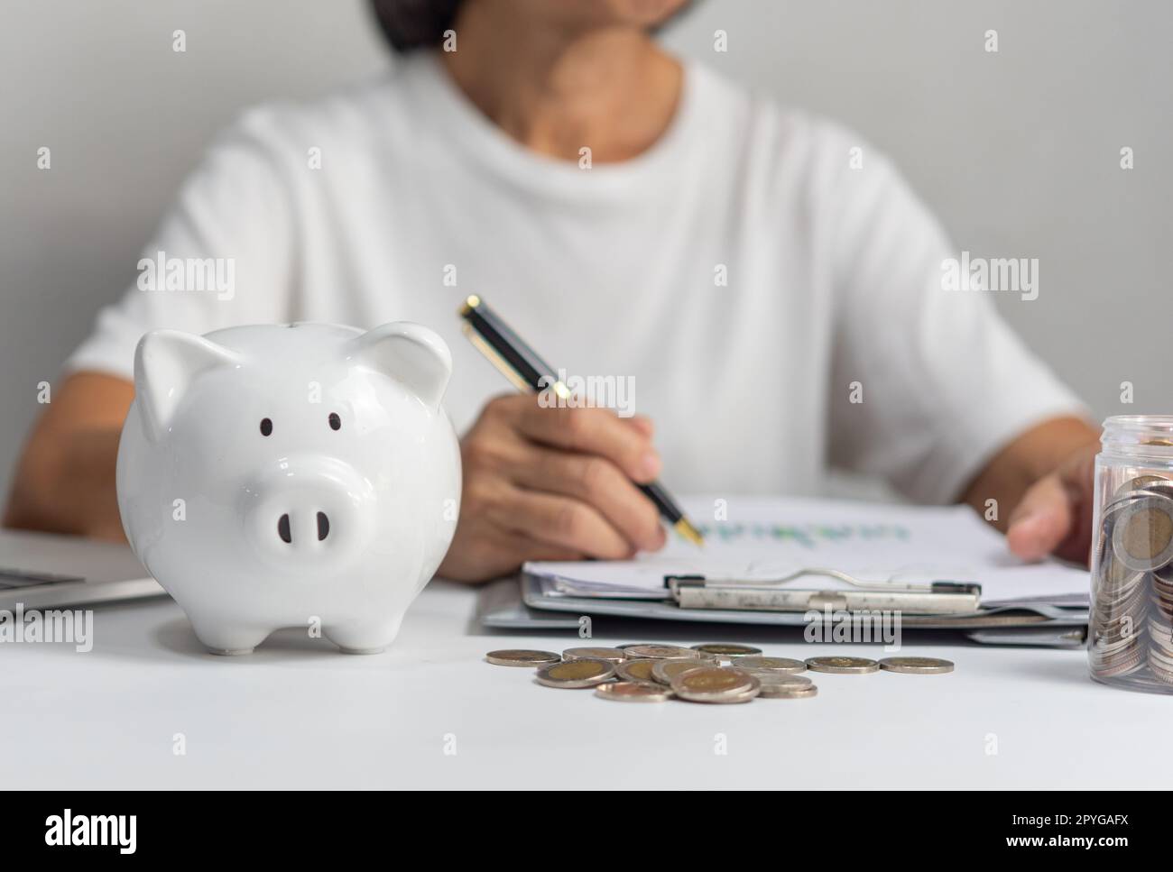 mujer que pone la moneda en la alcancía y ahorra dinero para el plan futuro y el concepto de fondo de jubilación. Foto de stock