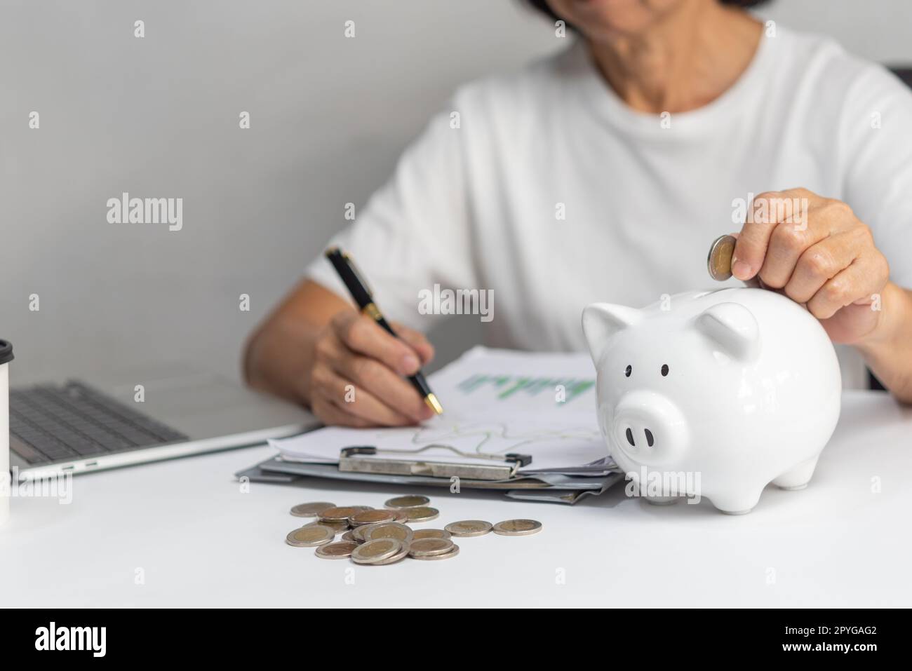 mujer que pone la moneda en la alcancía y ahorra dinero para el plan futuro y el concepto de fondo de jubilación. Foto de stock
