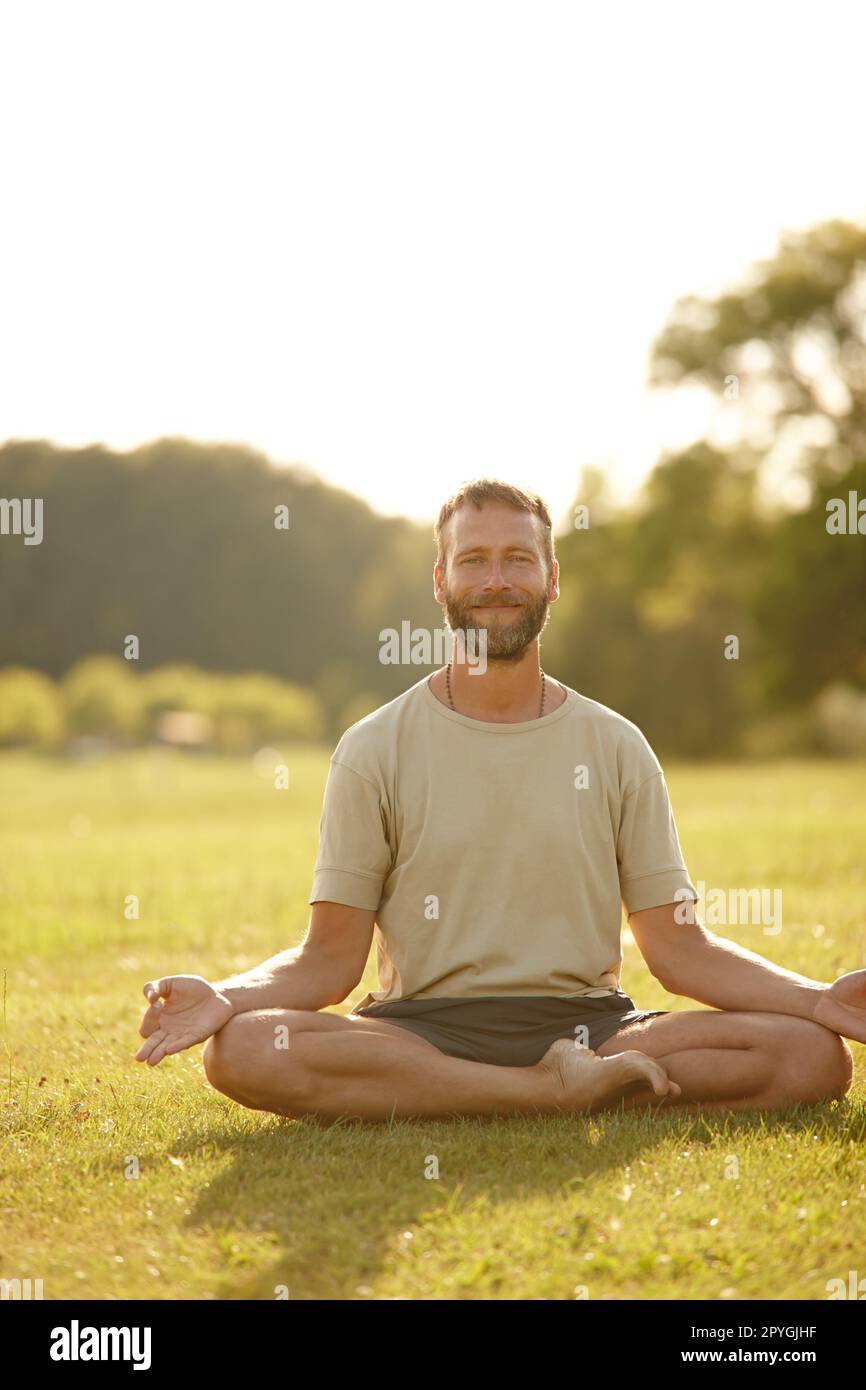 Apreciar la belleza de la naturaleza mientras haces yoga. Retrato de un hombre maduro guapo haciendo yoga al aire libre. Foto de stock