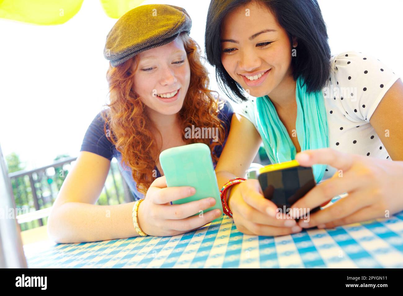 Comparación de aplicaciones. Dos chicas adolescentes sentadas afuera  enviando mensajes de texto en sus teléfonos celulares Fotografía de stock -  Alamy