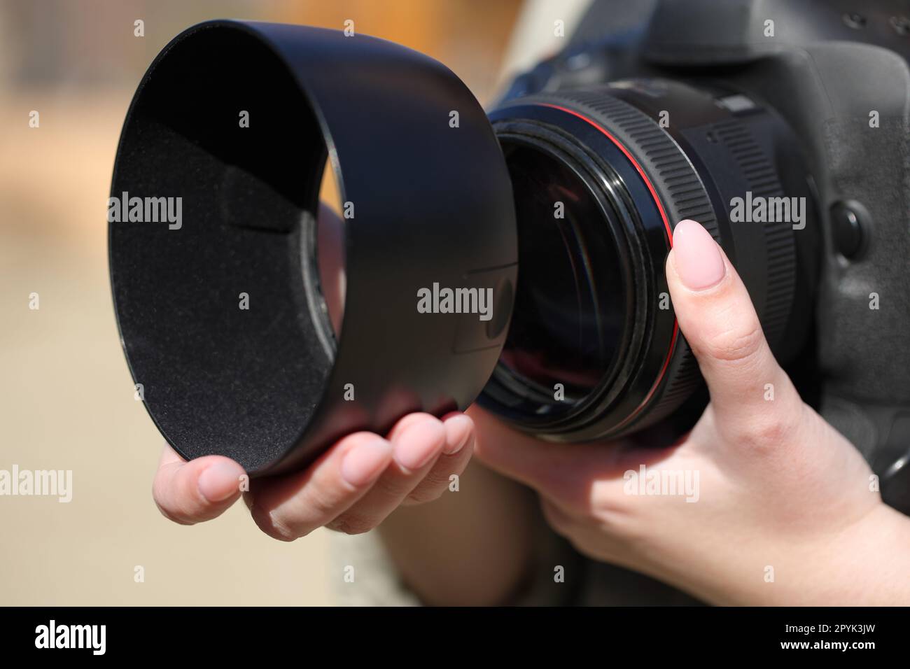 Mano del fotógrafo instalando la capucha de la lente Foto de stock