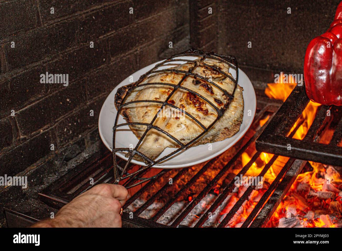 Cocinar pescado en jaulas de hierro sobre fuego de leña en el restaurante Brat en Londres, Reino Unido Foto de stock