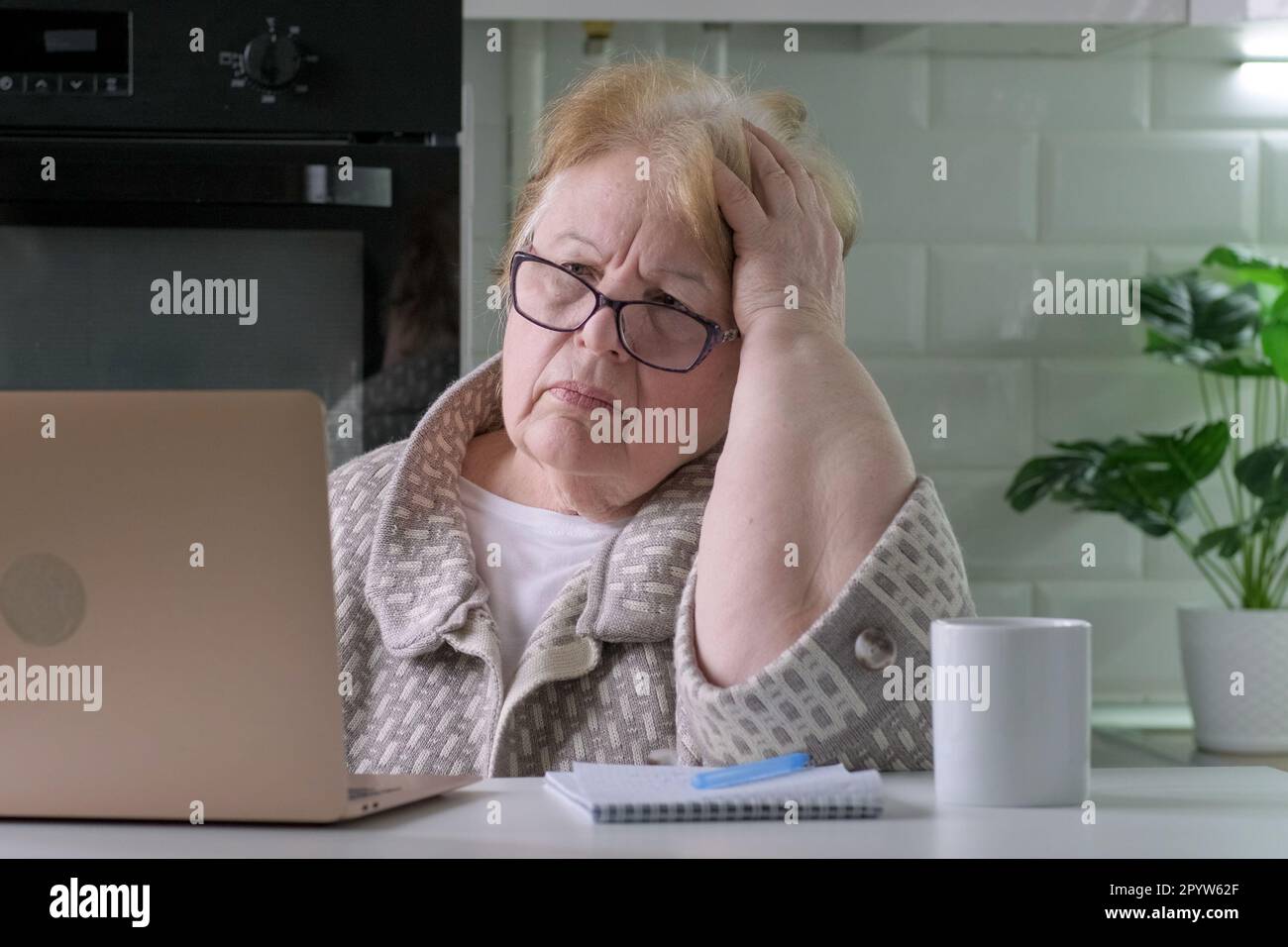 Vieja mujer preocupada en casa mirando la computadora portátil viendo malas  noticias Fotografía de stock - Alamy