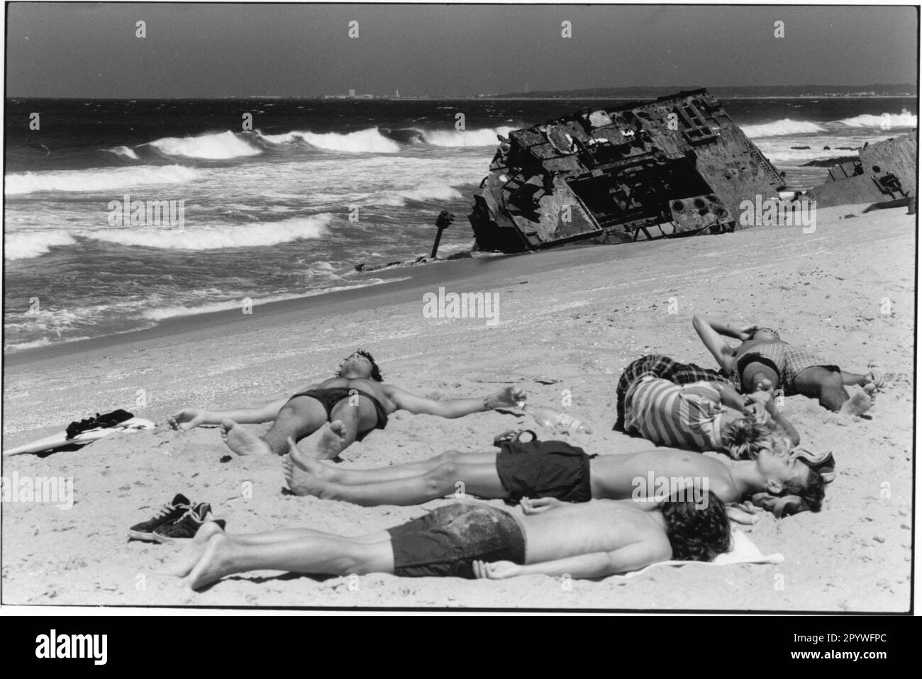 Uruguay, La Pedrera (Rocha). ''Trenzado''. Viaje y tiempo libre: Los jóvenes toman el sol en la playa de Rocha frente a un naufragio. Detrás de las olas del Atlántico. Escena de playa, blanco y negro. Foto, 1997.' Foto de stock