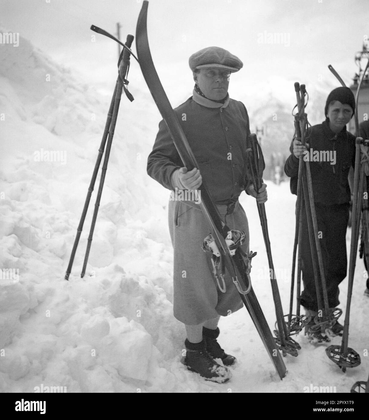 Dos esquiadores están de pie en la estación de montaña del teleférico. Foto sin fecha, probablemente en el invierno del 1933/1934. Foto de stock