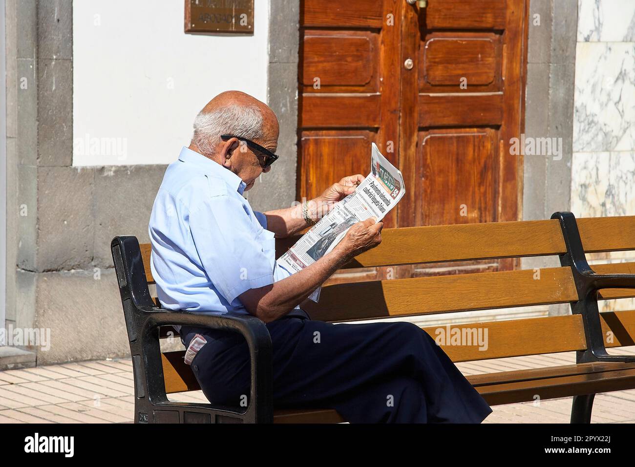 El hombre mayor con las gafas de sol se sienta en el banco del parque  leyendo el periódico, ciudad vieja, Vegueta, Las Palmas, capital, Gran  Canaria, Islas Canarias, España Fotografía de stock -