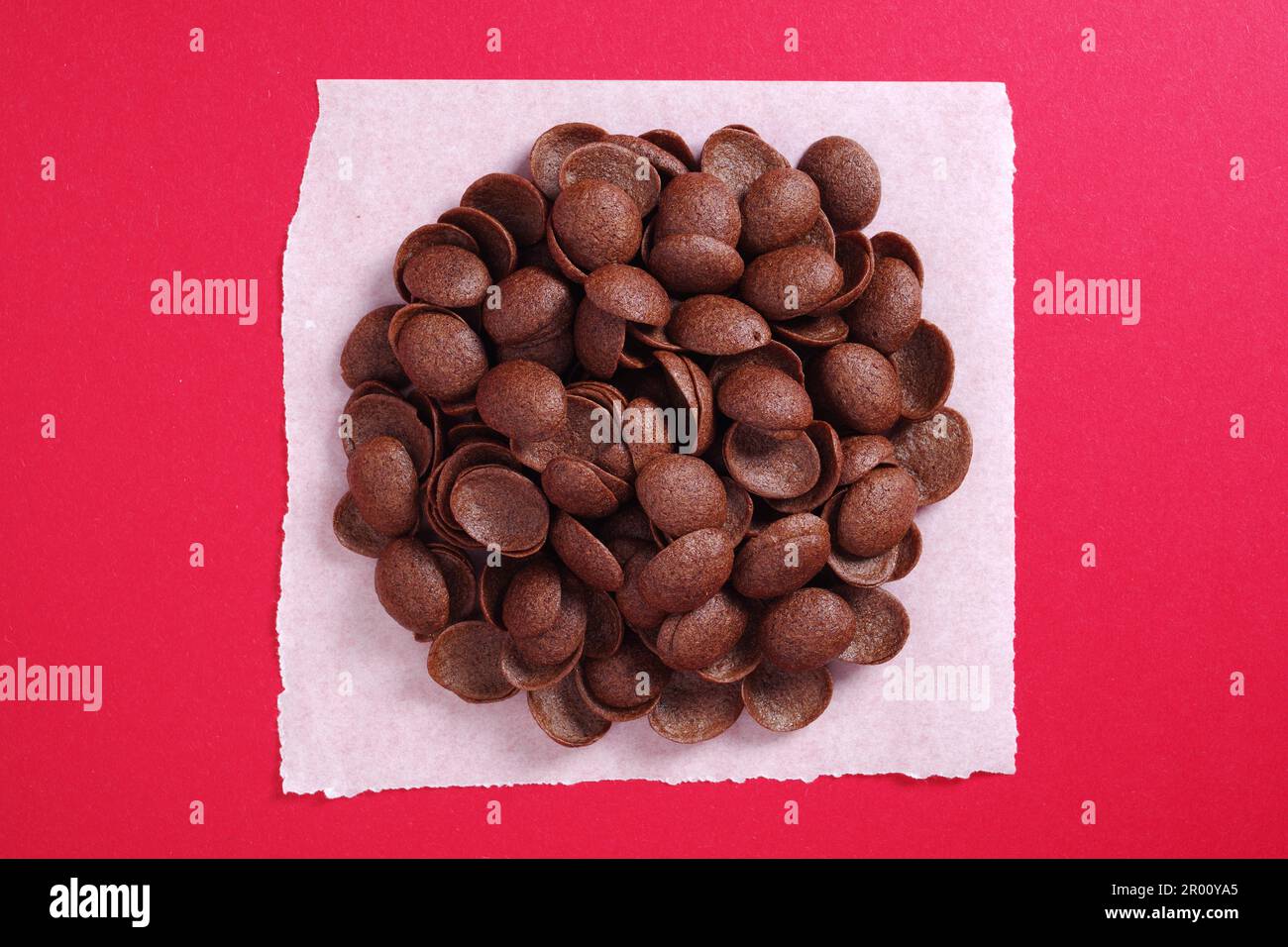 Desayuno de cereales de chocolate sobre fondo rojo. Carcasas esmaltadas. Vista superior Foto de stock