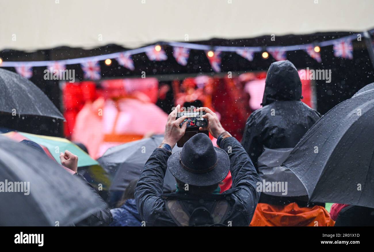 Brighton UK 6 de mayo de 2023 - Las multitudes ven bajo la lluvia la coronación del rey Carlos III en una pantalla grande en la Plaza Jubileo de Brighton hoy: Crédito Simon Dack / Alamy Live News Foto de stock
