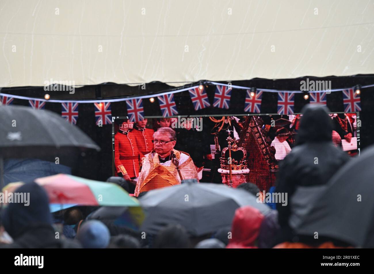 Brighton UK 6 de mayo de 2023 - Las multitudes ven bajo la lluvia la coronación del rey Carlos III en una pantalla grande en la Plaza Jubileo de Brighton hoy: Crédito Simon Dack / Alamy Live News Foto de stock