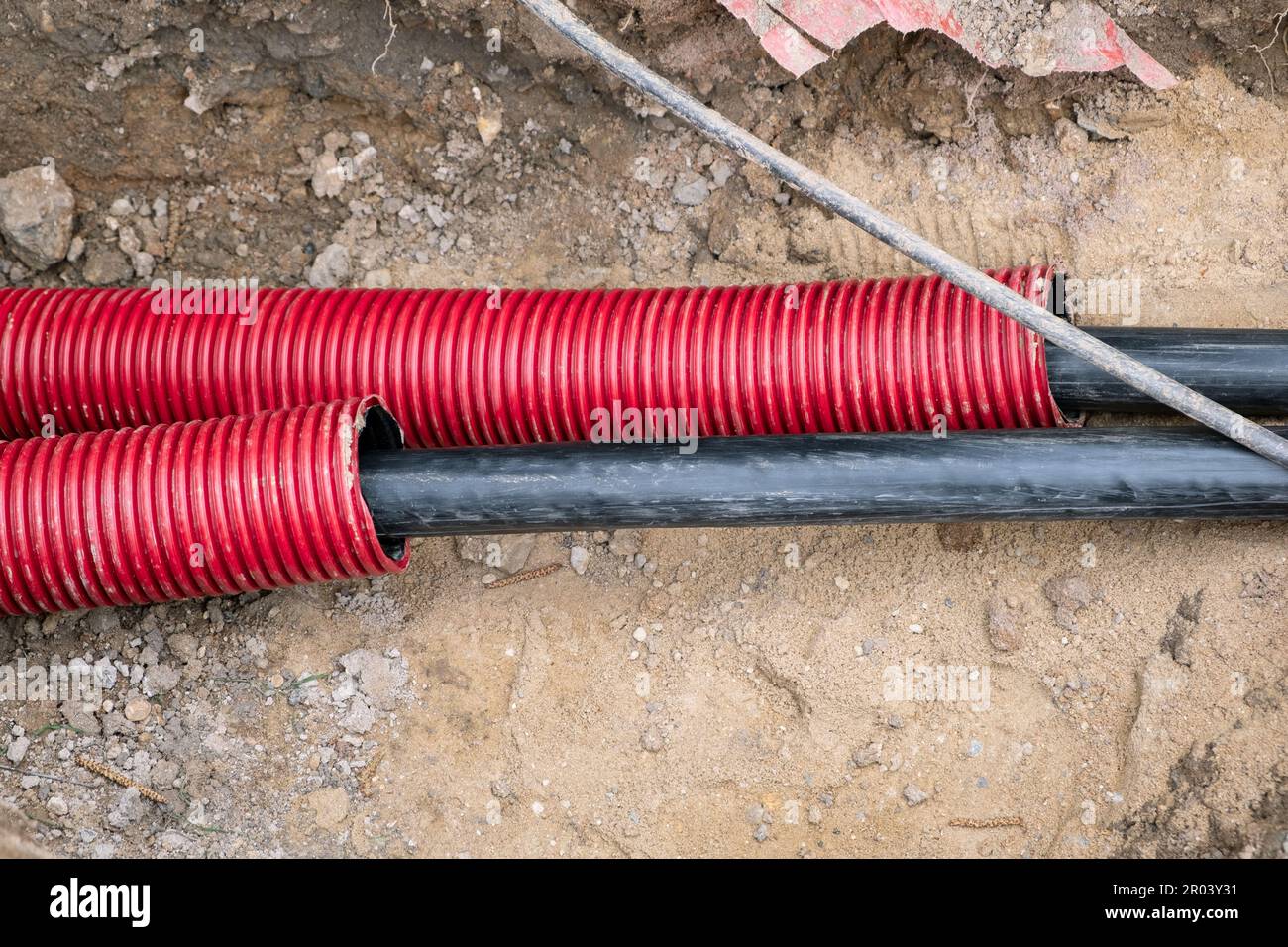 Los cables eléctricos en tubo corrugado rojo están enterrados bajo tierra  en la calle. instalación de infraestructura de cable eléctrico. Sitio de  construcción con Mucho Fotografía de stock - Alamy