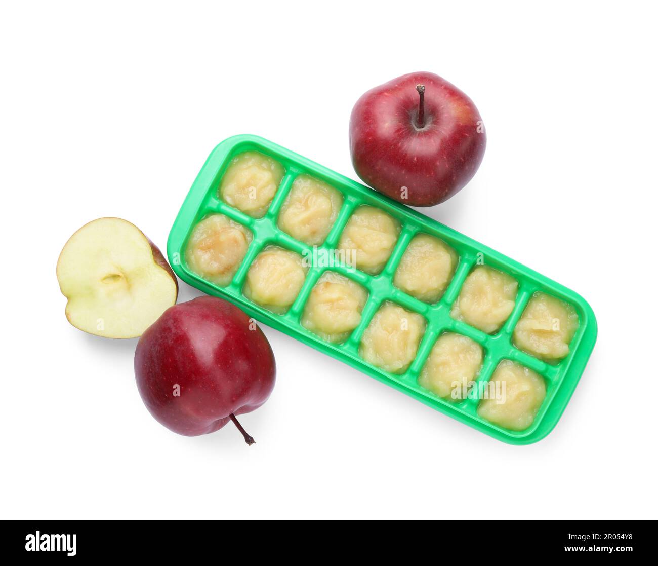 Puré de manzana en bandeja de cubitos de hielo y frutas de manzana frescas aisladas en blanco, vista superior. Listo para congelar Foto de stock