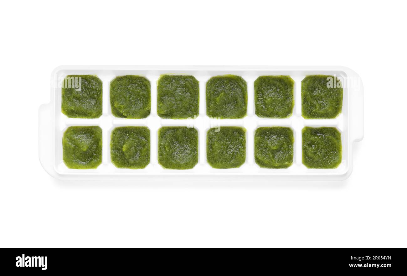 Puré de brócoli en bandeja de cubitos de hielo aislado en blanco, vista superior. Listo para congelar Foto de stock