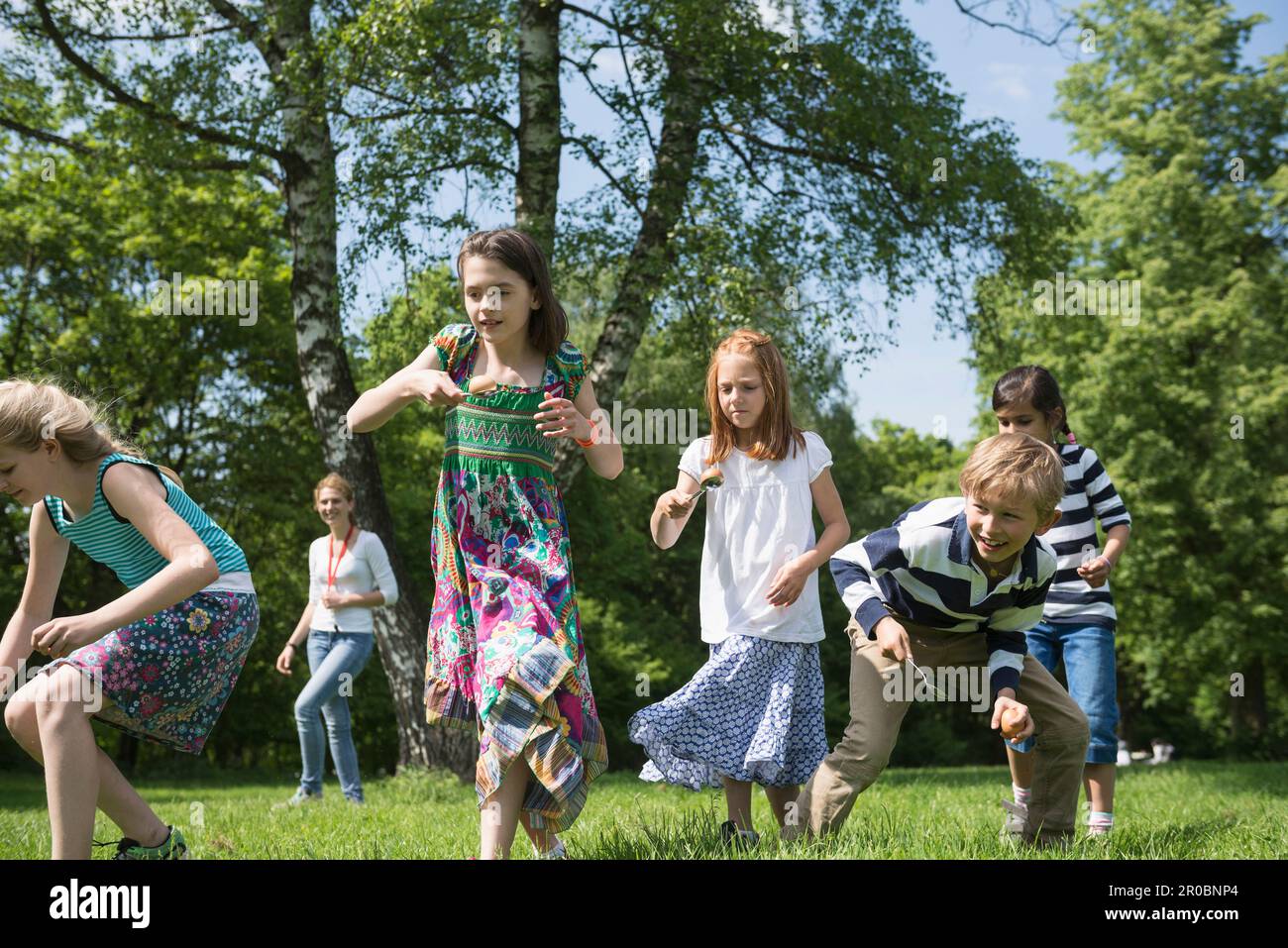 Grupo de niños que compiten en una carrera de huevo y cuchara en el parque, Munich, Baviera, Alemania Foto de stock
