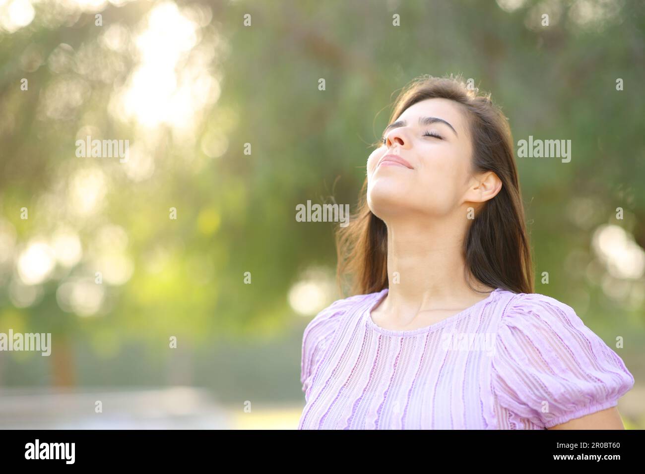Mujer satisfecha respirando aire fresco en un parque parado solo Foto de stock