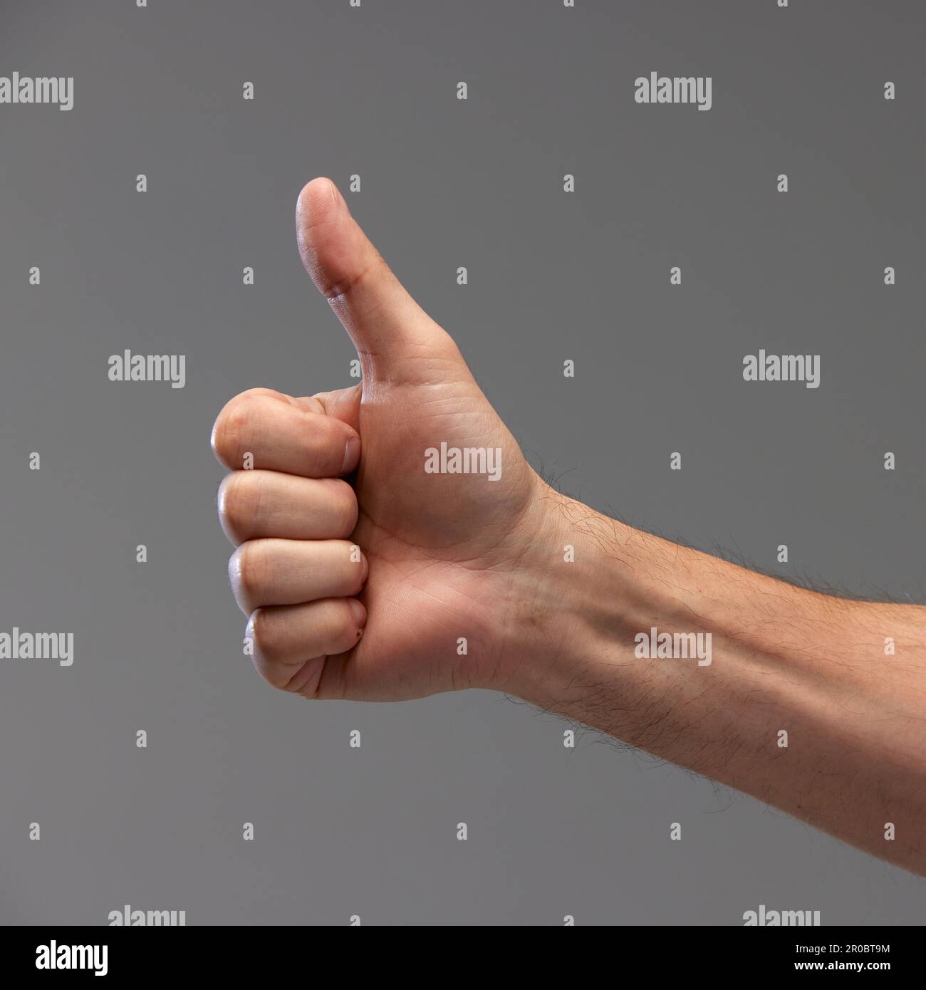 Mano masculina mostrando gesto de OK contra fondo gris. Buen tiempo, señales de aprobación, aceptación Foto de stock