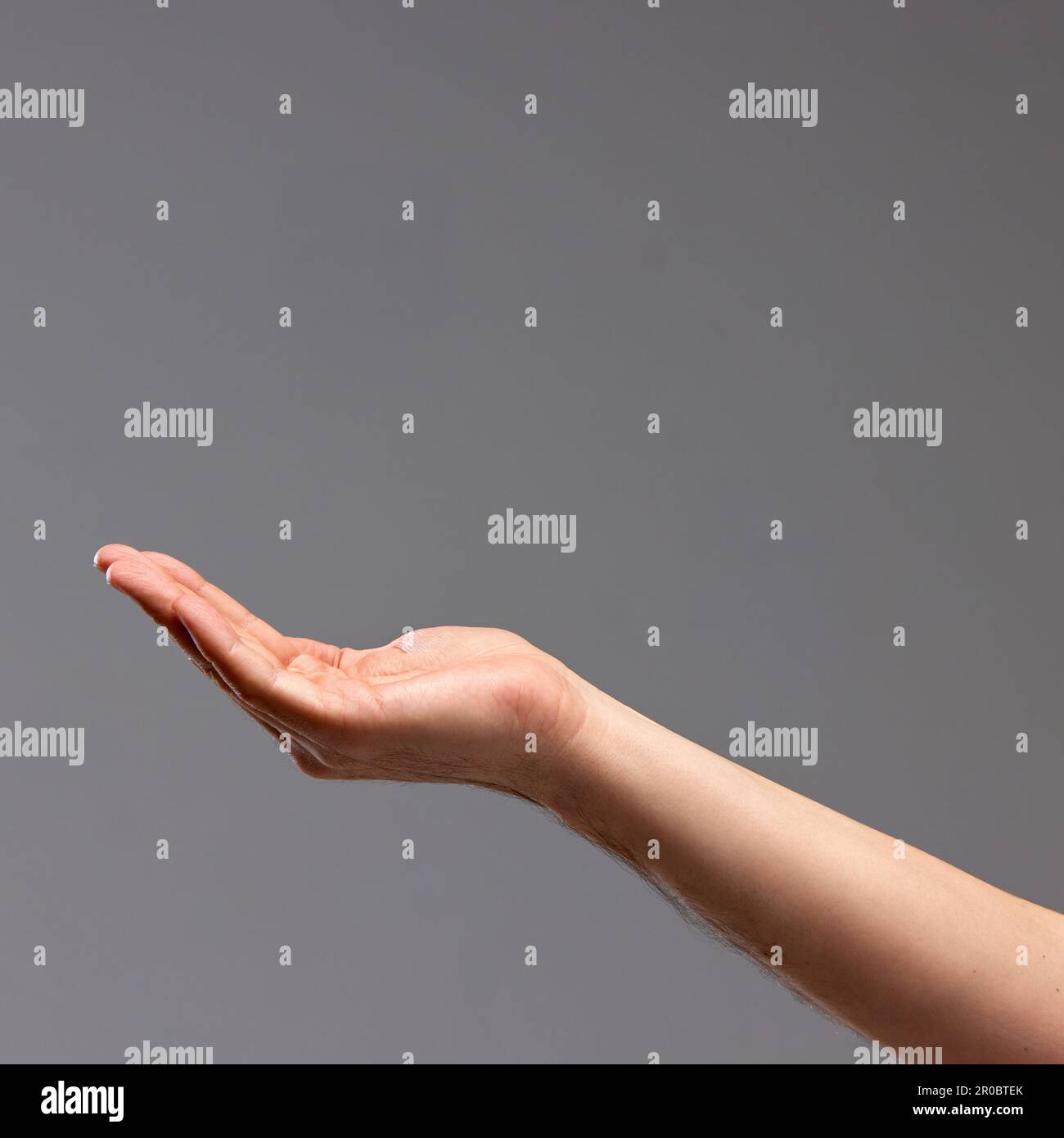 Mano femenina mostrando gesto contra fondo gris. Jugando con los gestos, haciendo figuras con las palmas Foto de stock