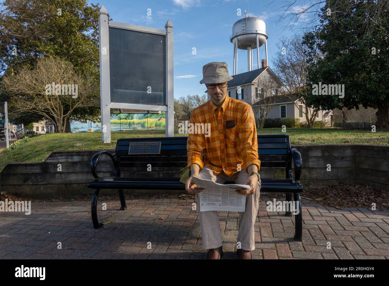 Escultura del mundo exterior de un hombre leyendo un periódico sentado en un banco en Gloucester Virginia Foto de stock