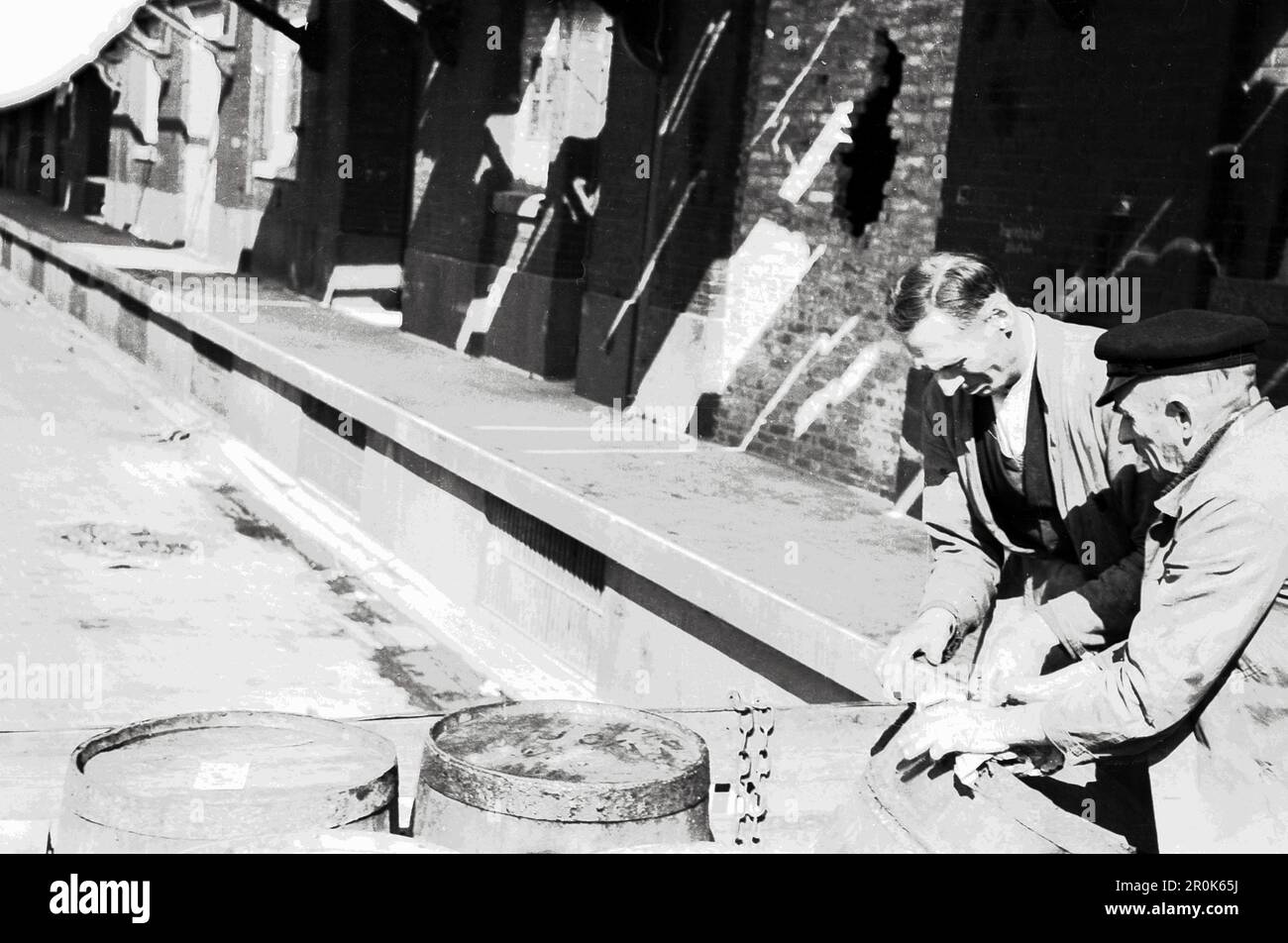 Fässer werden an einem Güterbahnhof aufgereiht im Berlin der Nachkriegszeit, Alemania 1947. Foto de stock
