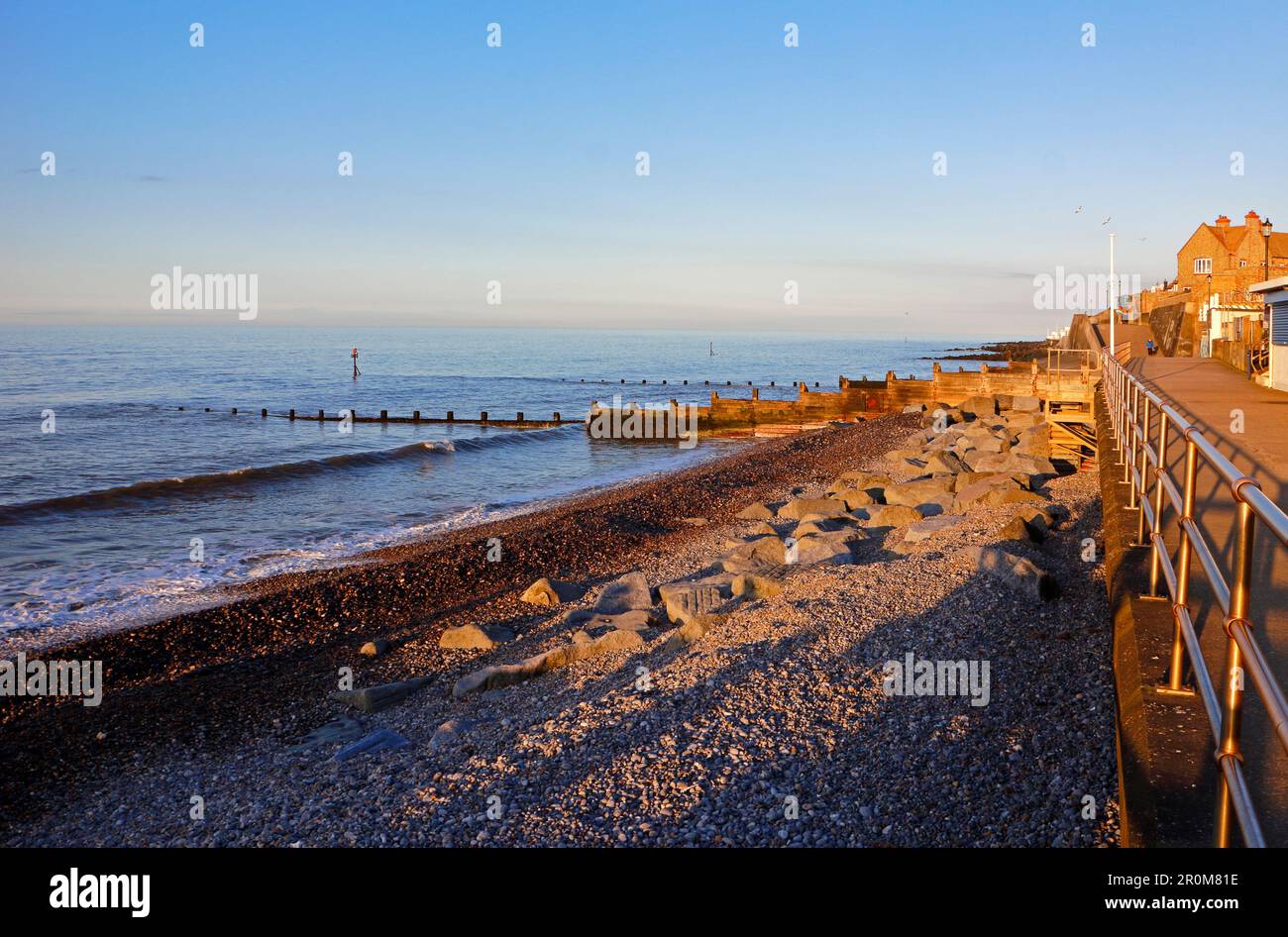 Sol al atardecer a lo largo de la playa y el paseo marítimo en la costa norte de Norfolk en Sheringham, Norfolk, Inglaterra, Reino Unido. Foto de stock