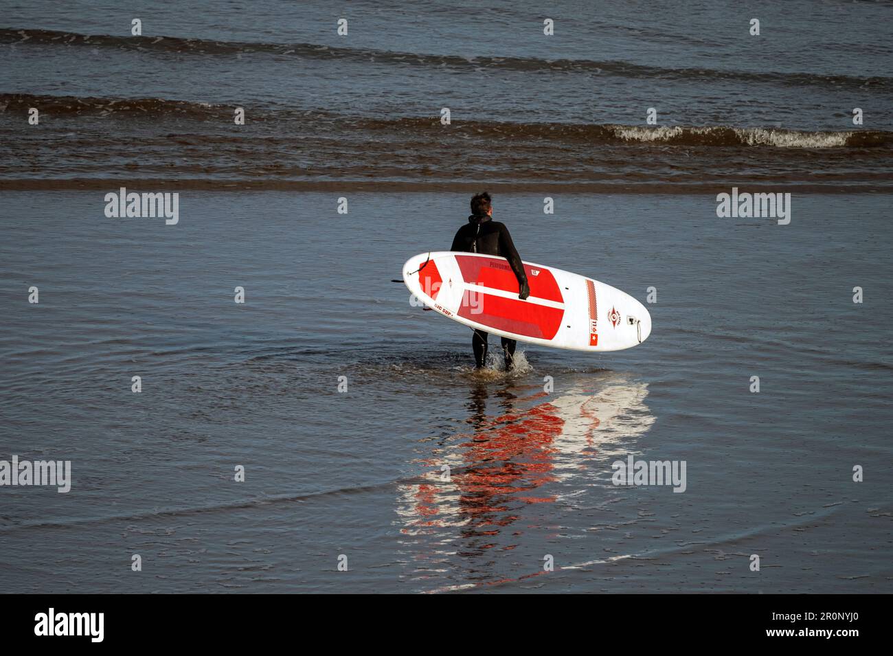 Un surfista rebotó en las arenas mojadas de la playa en la Bahía Norte de Scarborough. Foto de stock
